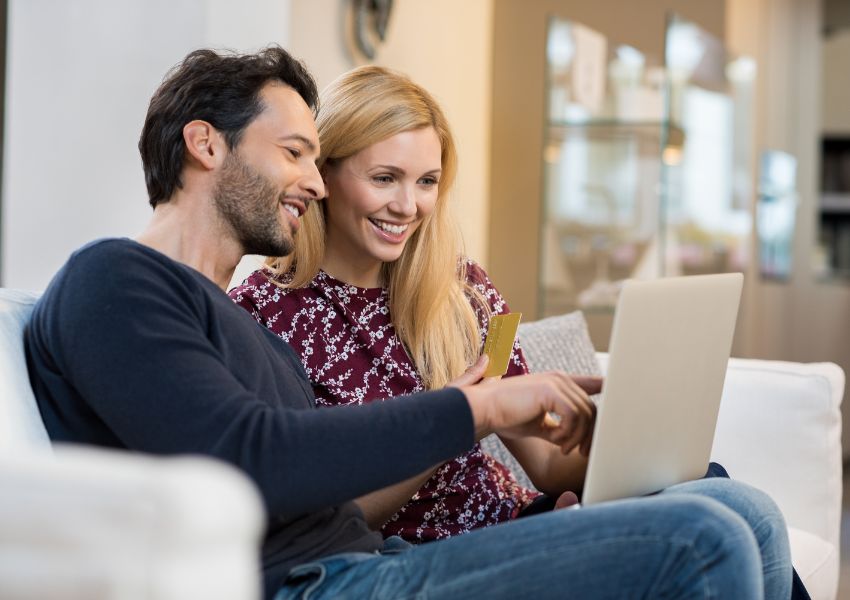 two tenant sitting on their white couch looking at a laptop and holding a credit card
